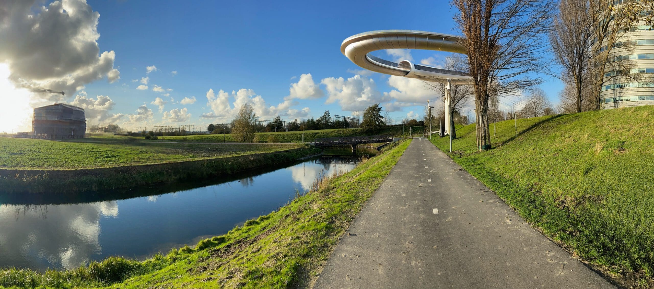 Innovatief Spoorontwerp over de Geniedijk Futuristisch spoorontwerp met een verhoogde infinity loop over de Geniedijk, met een waterpartij en groene omgeving.