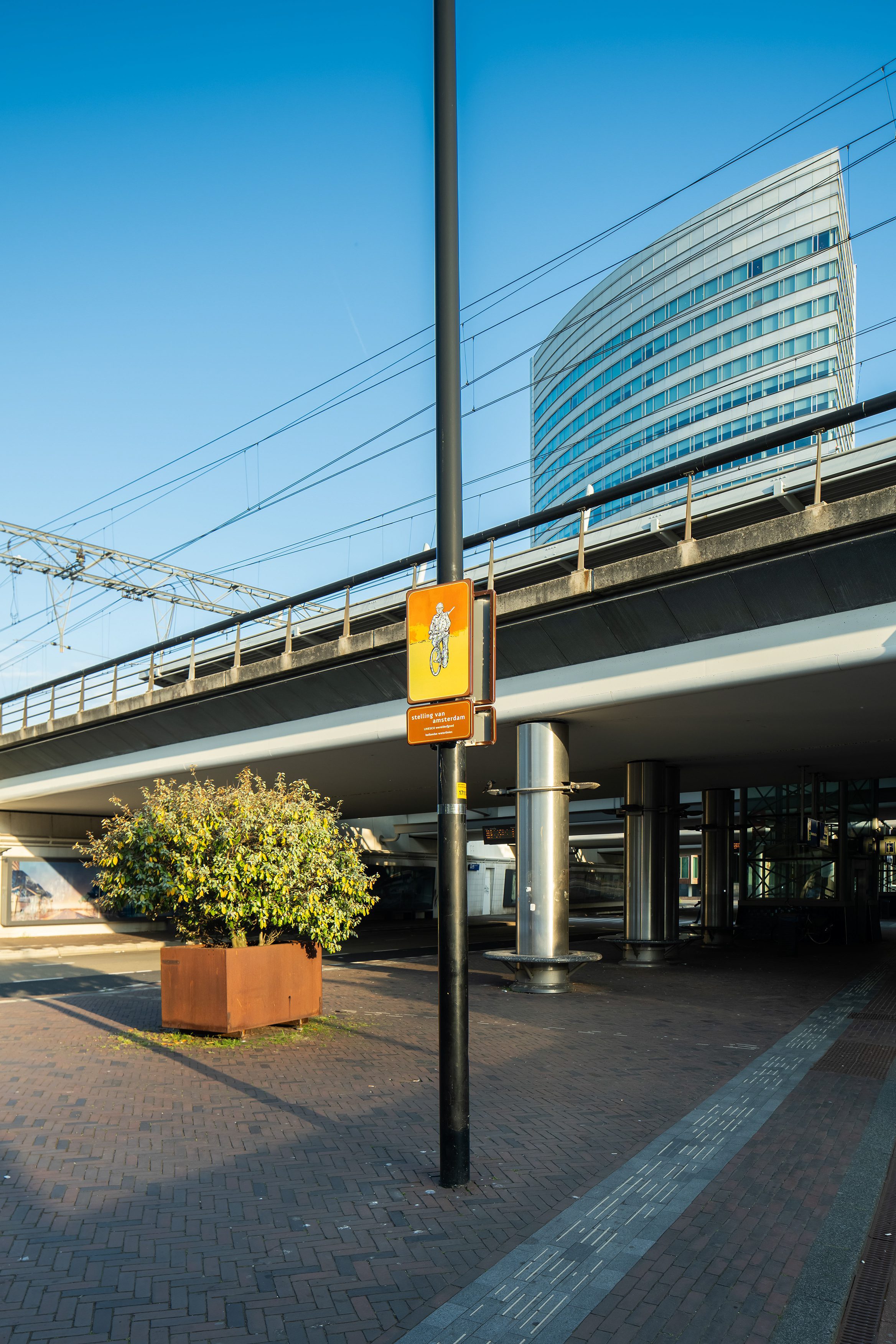 Beeldpaneel Soldaat op de fiets bij NS station Hoofddorp met spoorviaduct en kantoorgebouw op de achtergrond