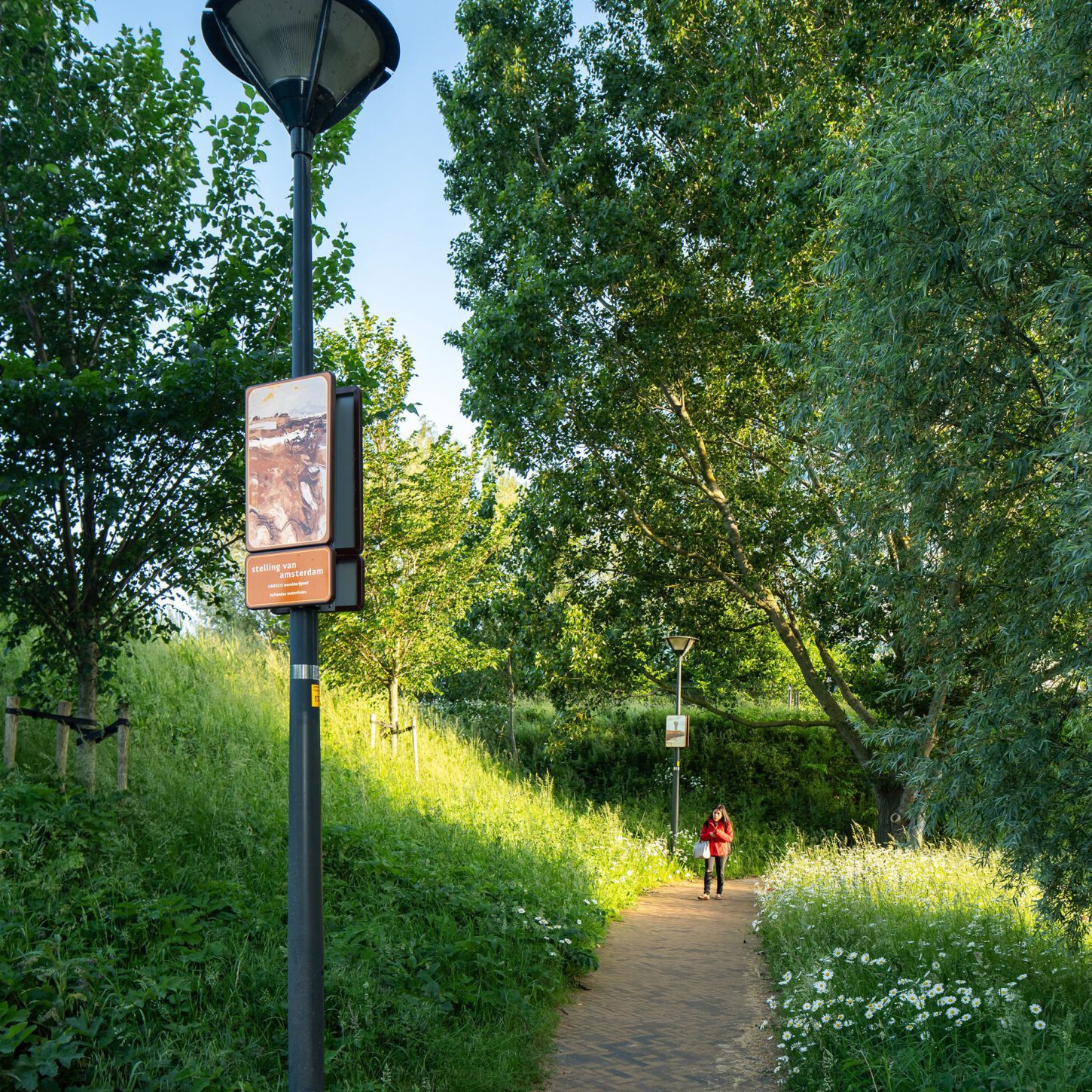 Beeldpaneel Modder en water langs wandelpad op de Geniedijk met wandelaar in rode jas