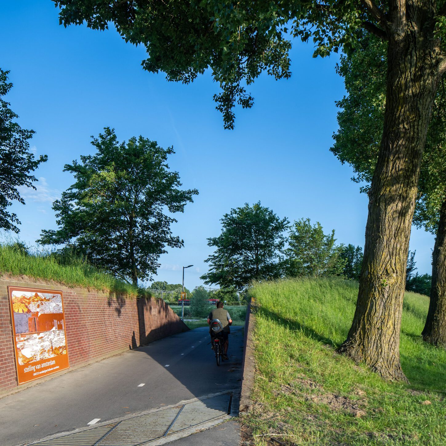 Beeldpaneel De Stelling bij de doorgang door de Geniedijk met passerende fietser