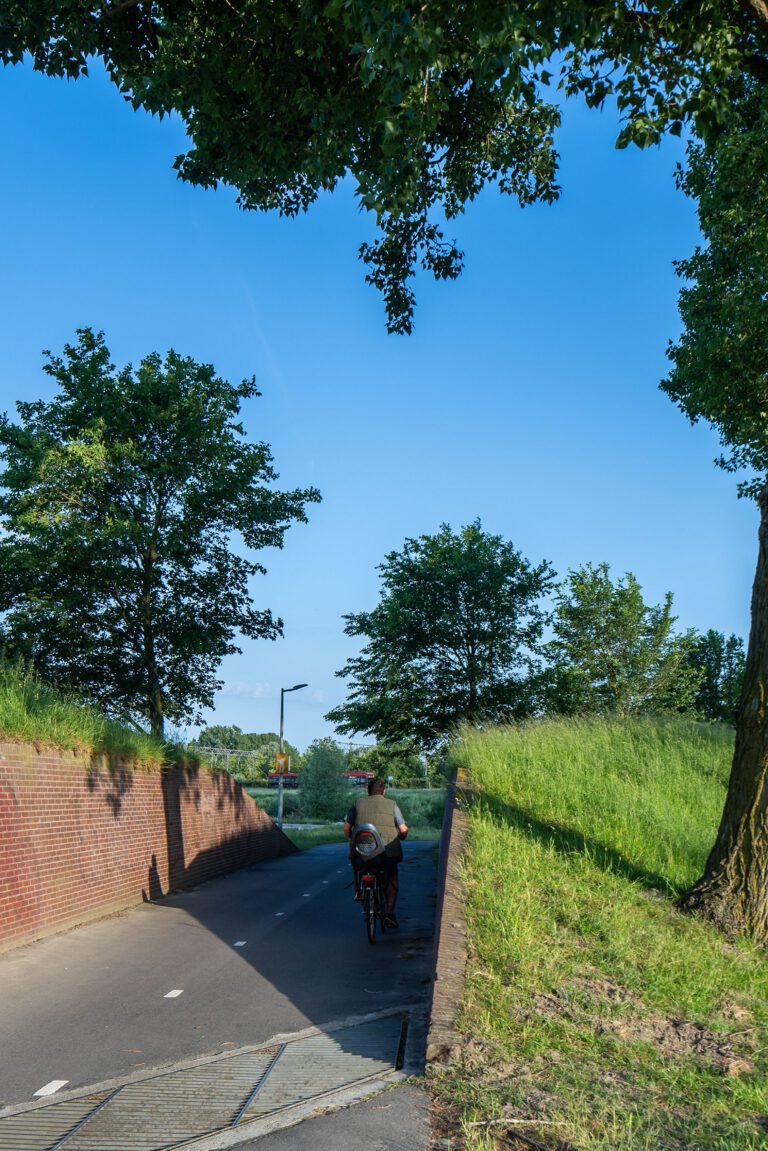 Beeldpaneel De Stelling bij de doorgang door de Geniedijk met passerende fietser