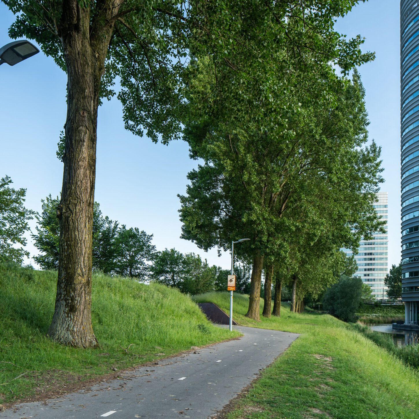 Beeldpaneel Soldaat met kind langs de Geniedijk met beeldpaneel Kanon verderop en moderne bebouwing van Hoofddorp