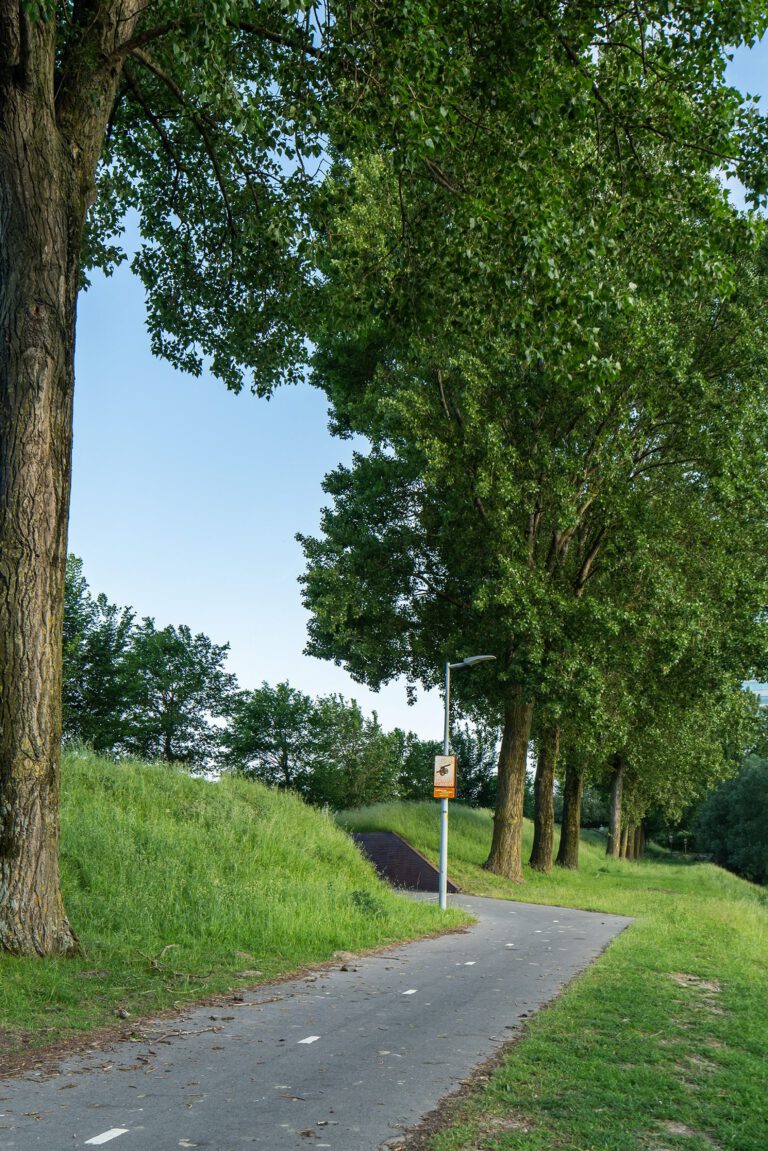 Beeldpaneel Soldaat met kind langs de Geniedijk met beeldpaneel Kanon verderop en moderne bebouwing van Hoofddorp