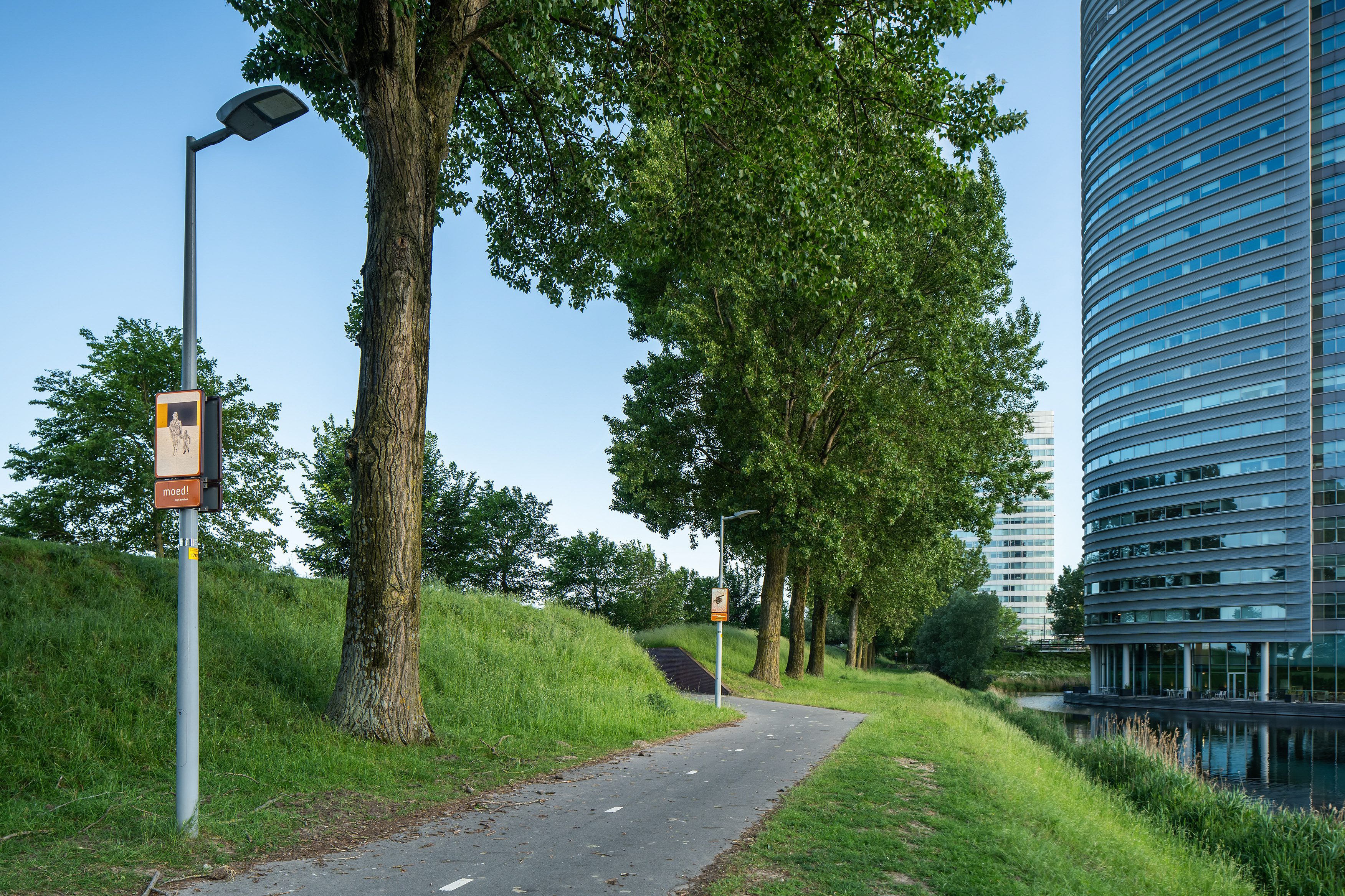 Beeldpaneel Soldaat met kind langs de Geniedijk met beeldpaneel Kanon verderop en moderne bebouwing van Hoofddorp