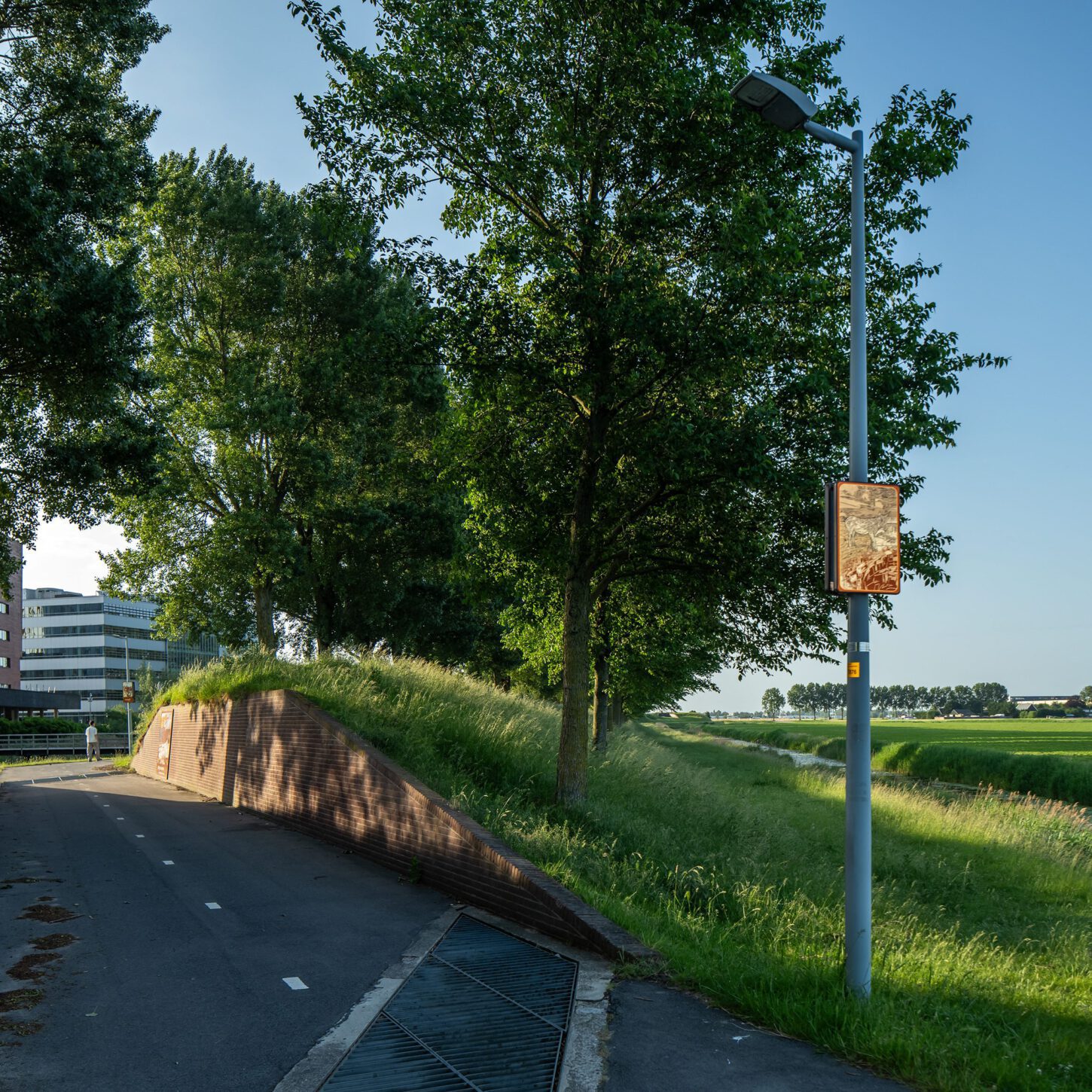Beeldpaneel De ezel langs de Geniedijk met doorgang door de dijk, watergang en open polderlandschap van de Stelling van Amsterdam