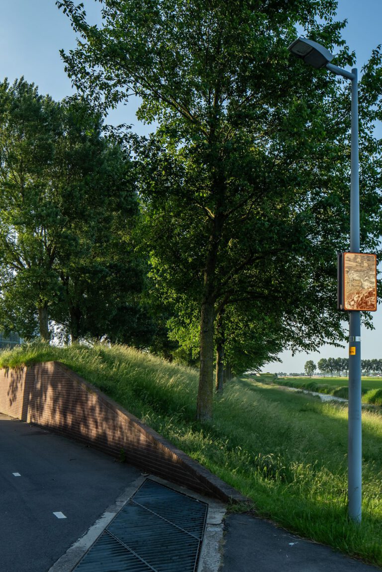 Beeldpaneel De ezel langs de Geniedijk met doorgang door de dijk, watergang en open polderlandschap van de Stelling van Amsterdam