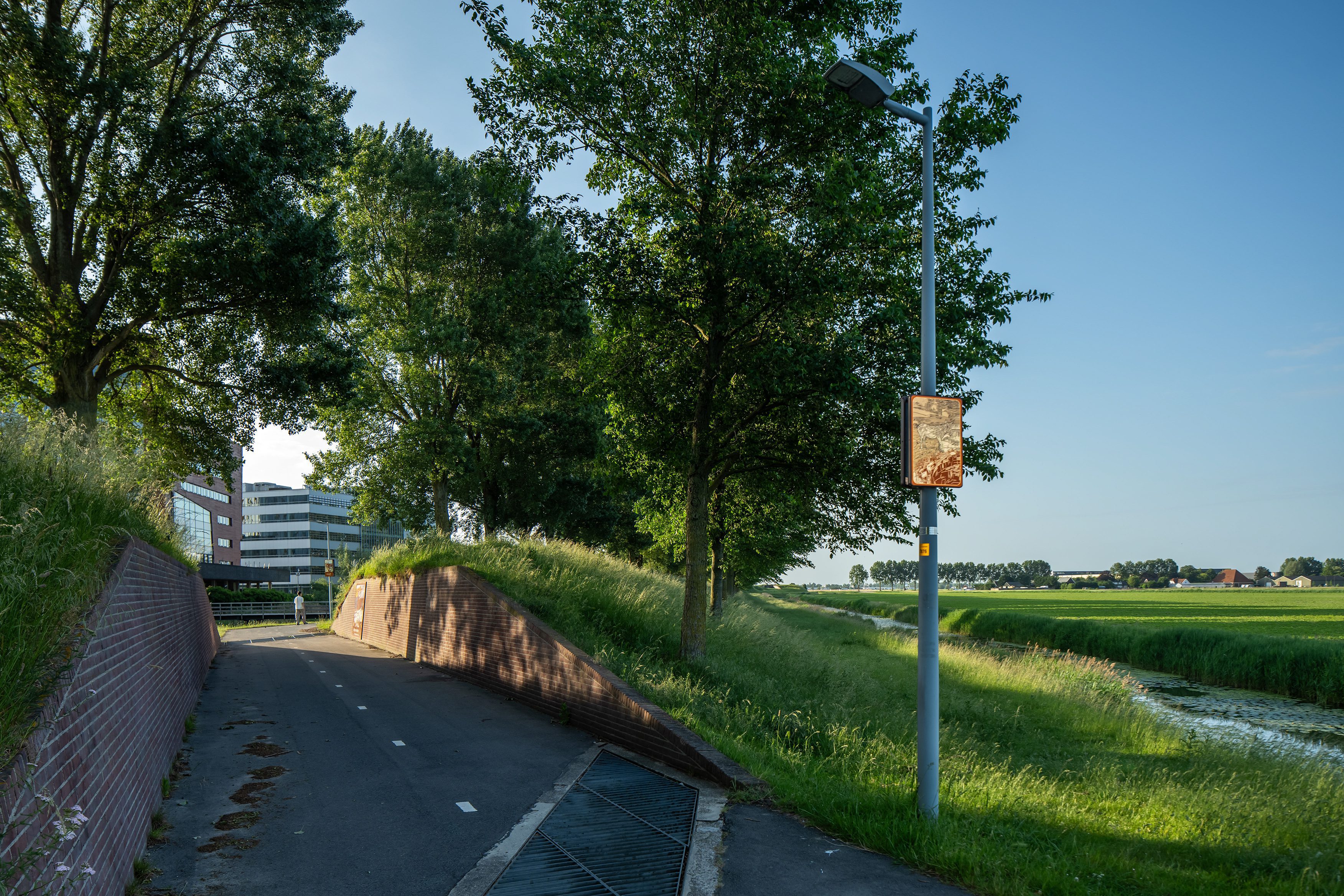 Beeldpaneel De ezel langs de Geniedijk met doorgang door de dijk, watergang en open polderlandschap van de Stelling van Amsterdam