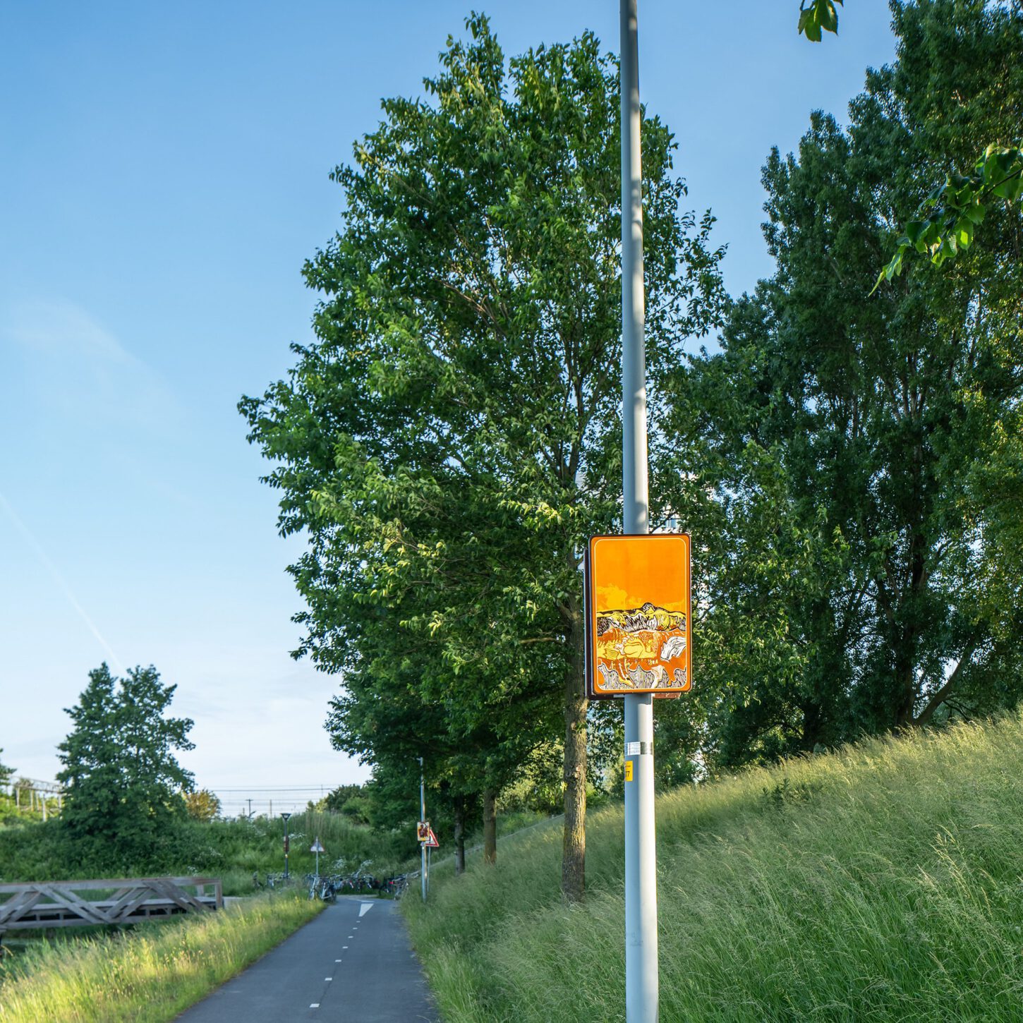 Beeldpaneel De golf langs de Geniedijk met fietspad, grasdijk en landschap van de Stelling van Amsterdam