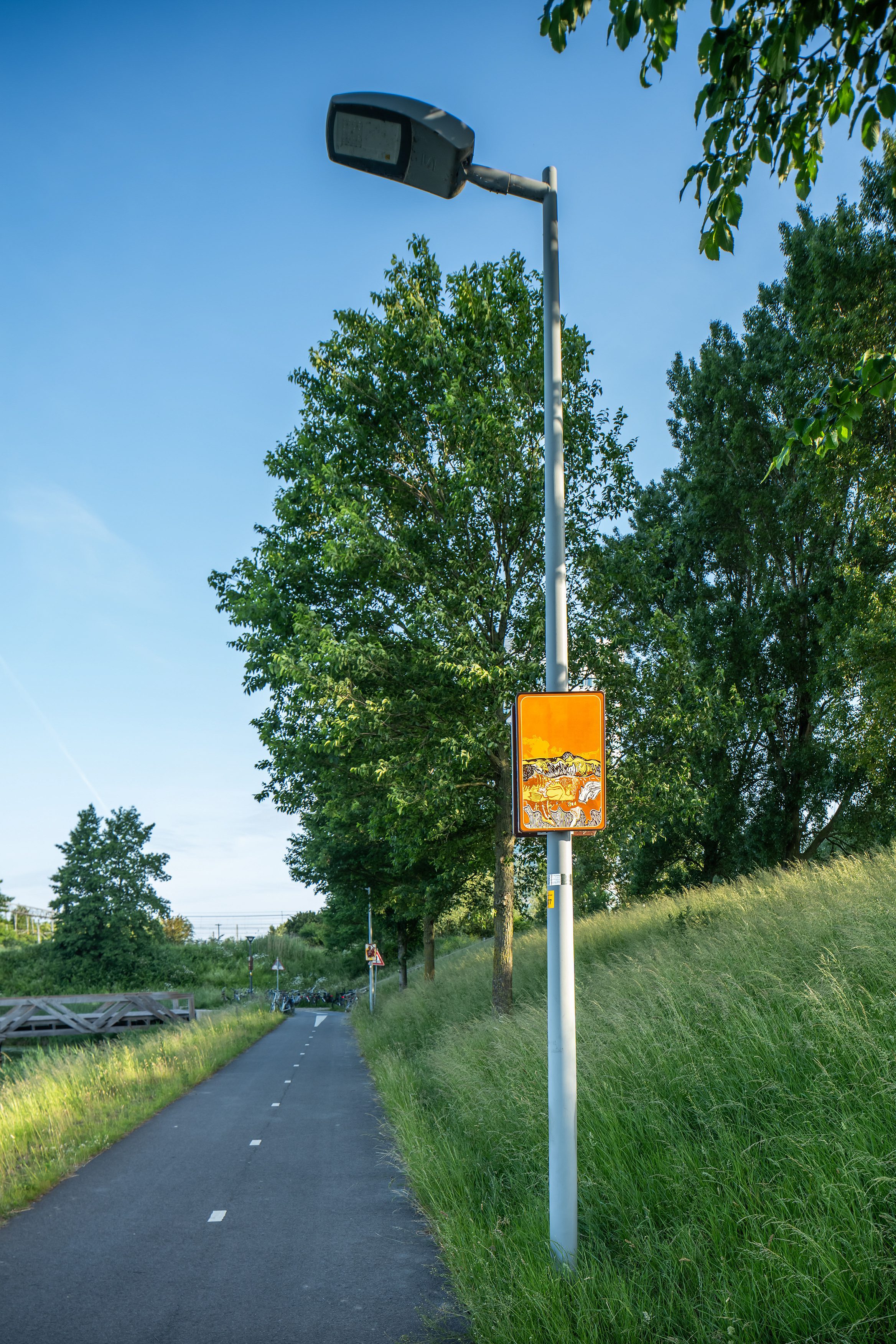 Beeldpaneel De golf langs de Geniedijk met fietspad, grasdijk en landschap van de Stelling van Amsterdam